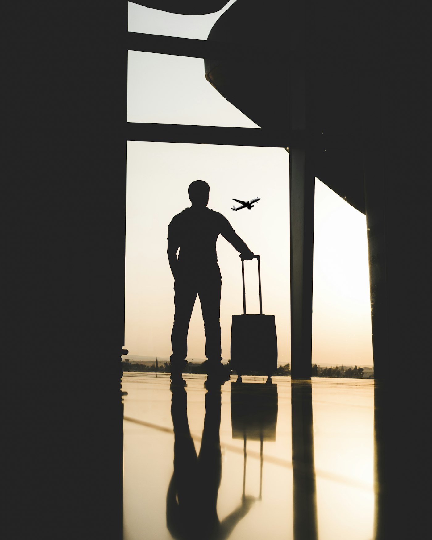 Silhouette of a traveler holding luggage inside an airport